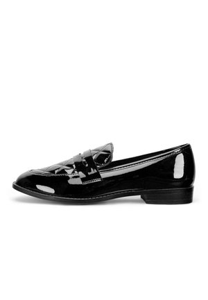 Mocasín de charol negro con tacón bajo y detalle de correa cosida, visto de lado sobre un fondo blanco.