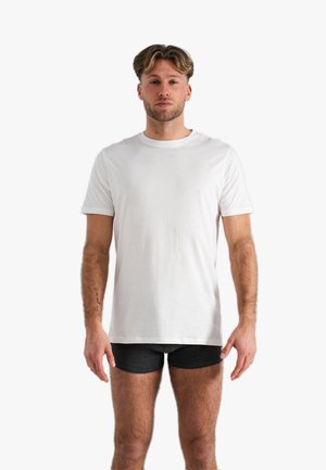 Witte kortekleurige katoenen t-shirt met een ronde hals, gepresenteerd op een mannelijk model. Het shirt heeft een relaxte pasvorm en een zachte textuur.