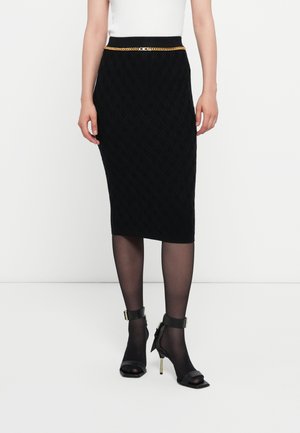 Mustat polvenmittaiset kynähameet, joissa on tekstuuritikkaukset, slim fit -malli ja kultaketjuvyö. Yhdistettynä mustiin nilkkahihnakenkiin.