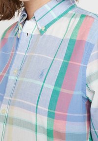 Camicia colletto di un blu chiaro con un motivo a quadretti multicolore caratterizzato da strisce verdi, rosa e crema. Piccolo logo ricamato sul tessuto.
