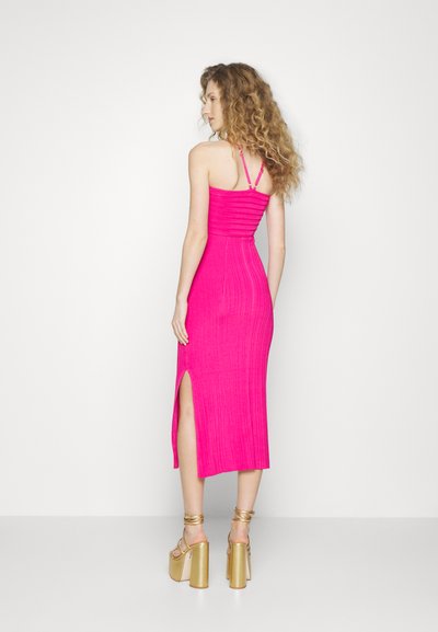 Ροζ εφαρμοστό φόρεμα με ριχά μανίκια, μήκους μέχρι τα γόνατα, με πλαϊνό άνοιγμα και υφασμάτινη υφή. Συνδυασμένο με χρυσά πλατφόρμα παπούτσια.