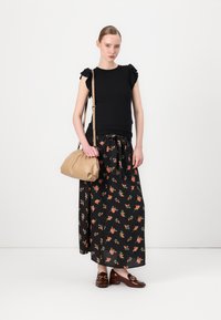 Top nero con maniche a volant, gonna maxi nera floreale, mocassini marroni e una borsa beige con design arricciato. Accessori semplici.