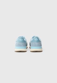 Lyseblå sneakers med en kombination af glatte og teksturerede materialer, forstærket hæl og en hvid mellemsål. Ikonisk tre-stribes-logo på hælen.