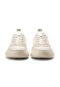 Ein Paar beige und weiße Sneakers mit dicken strukturierten Sohlen, Schnürsenkeln und Markenlaschen, die nach vorne zeigen, auf einem weißen Hintergrund.