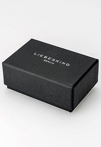Zwarte textuur rechthoekige doos met een gladde afwerking waarop "LIEBESKIND BERLIN" in het wit op de voorkant is gedrukt. Geen zichtbare hardware.