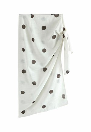 Weißer Wickelrock mit schwarzen Punkten, seitlich gebunden, mit weichen Stofffalten drapiert.