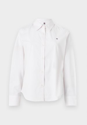 Bijela košulja dugih rukava od prugaste tkanine, koja ima ovratnik, zakopčavanje na gumbe i mali logo na prsima.