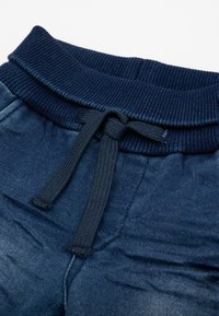 Pantaloni sportivi blu scuro con vita a coste, cordino regolabile e una morbida texture simile al denim.