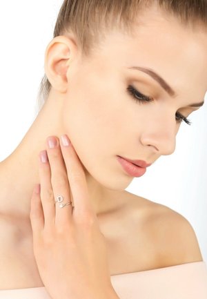Delicate silver adjustable ring featuring a "D" initial and a small arrow detail. Model touches her neck, displaying subtle nail polish.
