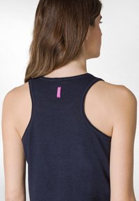 Navyblå ärmlös topp i mjukt tyg, med rund Halsringning och en liten rosa logotags på baksidan. Slät textur.