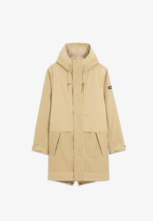 Parka beige à capuche avec fermetures à pression à l'avant, bracelets réglables aux poignets, deux poches avant à rabat et une petite écusson sur la manche gauche.