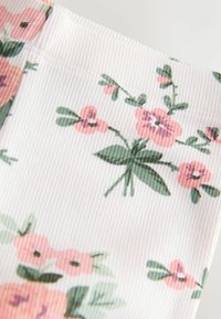 Virágos anyag bordázott textúrával pasztell színekben. A mintán rózsaszín virágok zöld levelekkel fehér háttéren.