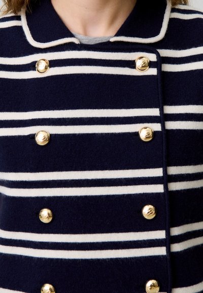 Cappotto doppiopetto a strisce blu navy e bianche con colletto, caratterizzato da bottoni dorati e una texture morbida. Vista ravvicinata della parte superiore del capo.