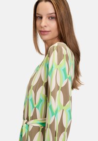 Muster Kleid aus leichtem Material in Grüntönen, Beige und Creme, mit einem Gürtel in der Taille, langen Ärmeln und einer lockeren Passform.