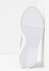 Valkoiset urheilukengät, joissa on teksturoitu kumipohja, beige korostus, jossa on ruutupattern ja logo sivussa.