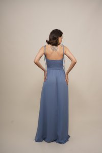 Long, flowy blue dress with a smocked bodice and adjustable straps. Back view, featuring a tattoo and smooth fabric texture.