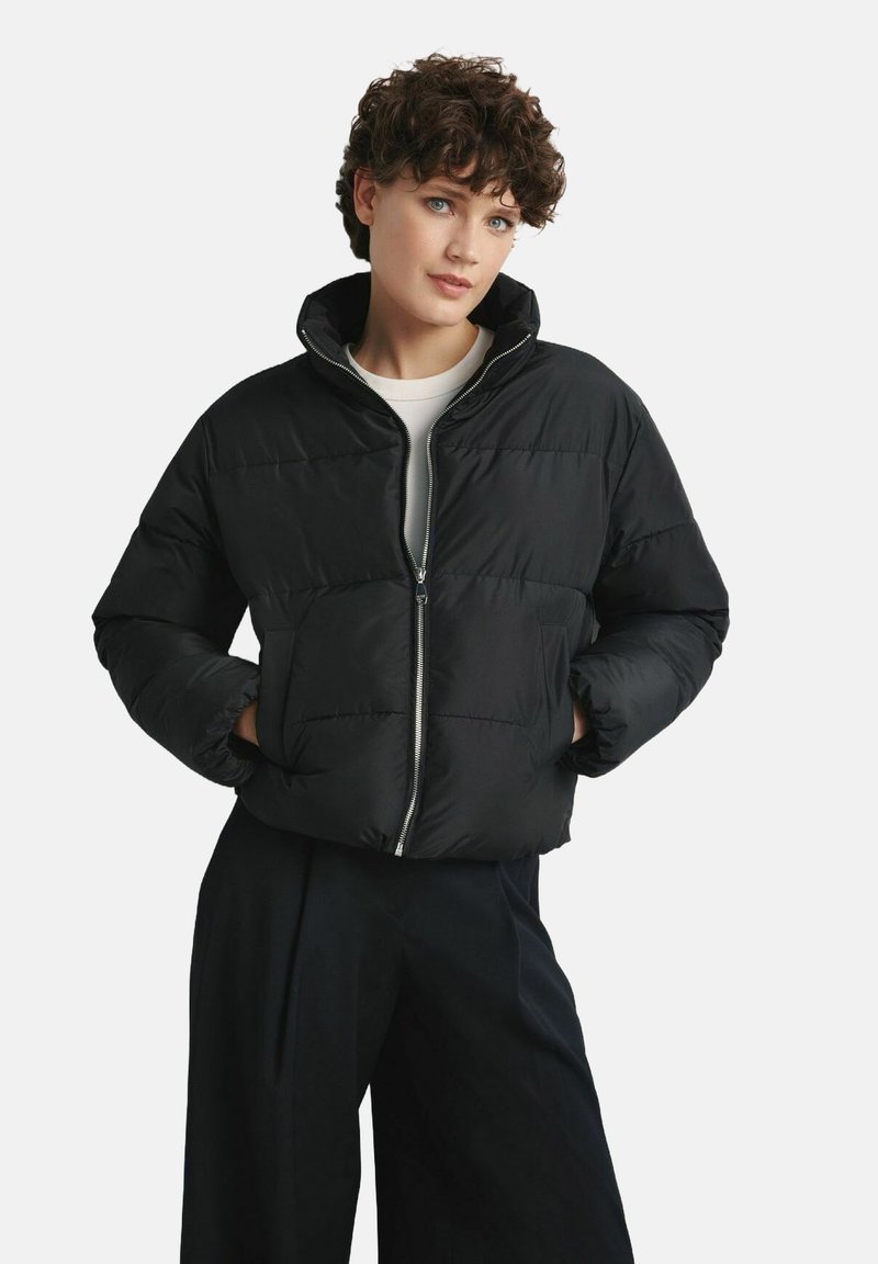 Czarna kurtka puchowa z wysokim kołnierzem, zapinana na zamek z przodu, z dwoma bocznymi kieszeniami. Posiada pikowany wzór i krótki krój.