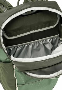 Zaino in tessuto verde con interni grigi. Presenta un ampio scomparto principale aperto, tasca orizzontale con zip, dettagli in rete elastica e coulisse.