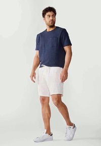 Navy textured short-sleeve shirt with a pocket, paired with light-colored shorts and white sneakers. Casual, relaxed fit.
