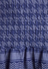 Modrá texturová tkanina s nařaseným designem, horizontálními pruhy a cikcak vzorem podél dolního okraje. Měkká, tkaná textury.