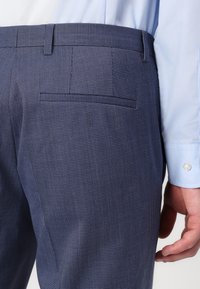 Tumši zili rakstāmi bikses ar līdzenu priekšpusi, sānu kabatām un aizmugurējo kabatu ar diskrētu apmali. Gluda auduma, pielāgots piegriezums.