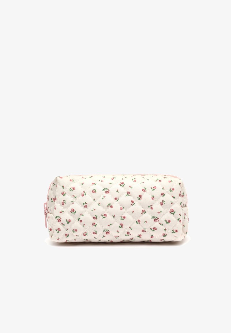 Trousse blanche rectangulaire matelassée avec un motif de roses roses et une fermeture éclair rose sur le bord supérieur, placée sur un fond blanc.
