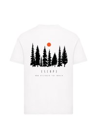 White cotton t-shirt featuring a black forest graphic with an orange sun and the text "ESCAPE AND DISCOVER THE WORLD" in bold font.