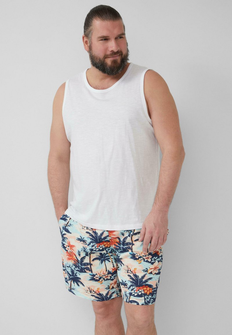 Weißes ärmelloses Tanktop und bunte Badehorts mit einem tropischen Blumen- und Palmenmuster. Die Shorts haben einen elastischen Bund.
