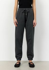 Mörkgrå sweatpants med elastisk midja och muddar, utrustade med dragsko, sidofickor och en slät, mjuk textur.