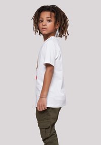 White cotton t-shirt with short sleeves, featuring a colorful graphic design; paired with olive green cargo pants.