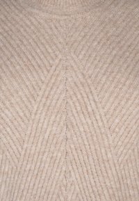 Beige gestrickter Pullover mit einem strukturierten Zickzackmuster, hohem Kragen und gerippten Details im gesamten Stoff. Weiches, gemütliches Material.
