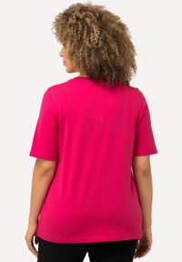 Camiseta rosa de manga corta con cuello redondo, textura suave y un corte relajado, vista desde atrás. Diseño sencillo sin patrones.