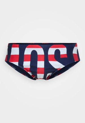 Costumi da bagno navy con lettering audace rosso e bianco. Il materiale è elastico e liscio. Presenta un design a vita bassa e una cintura elastica.