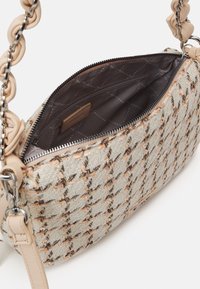 Sac à main rectangulaire tissé beige et marron avec une fermeture éclair, une chaîne et une bandoulière en cuir, montrant un intérieur en tissu foncé à motifs avec poche zippée.