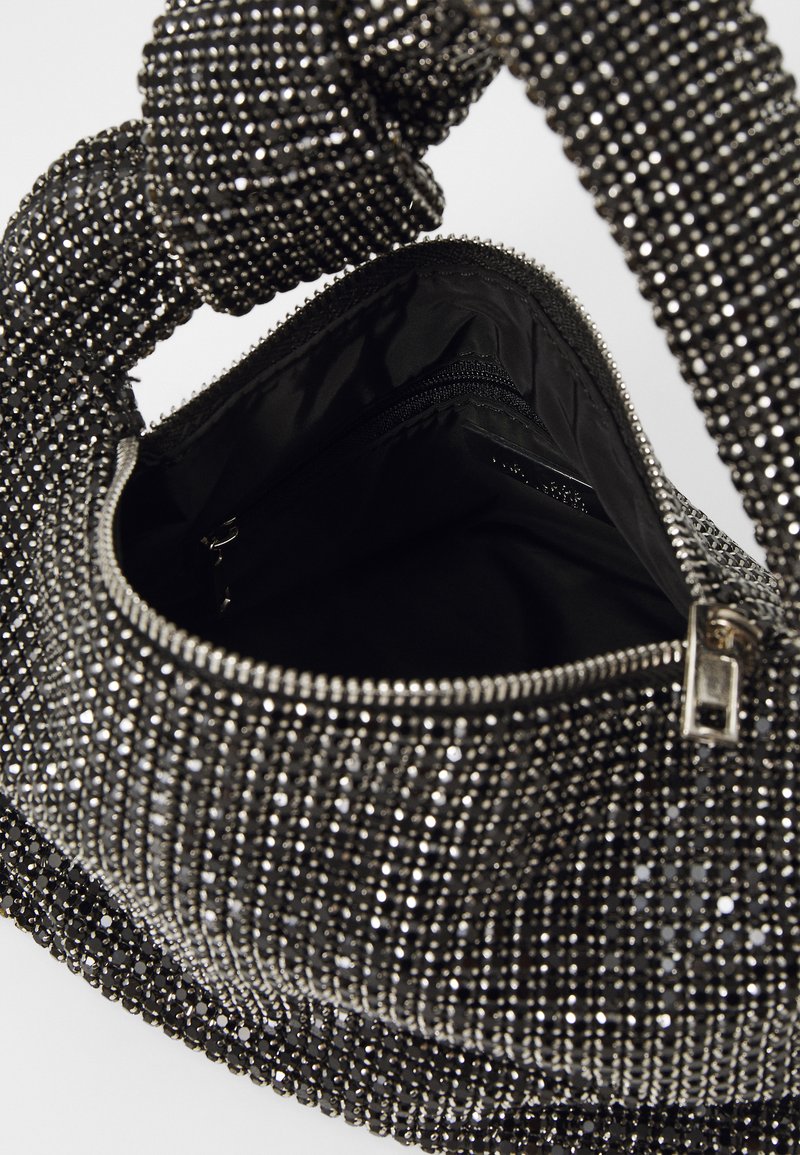 Borsa nera coperta di strass metallici, con chiusura a zip e manico testurizzato annodato. L'interno presenta una tasca con zip.