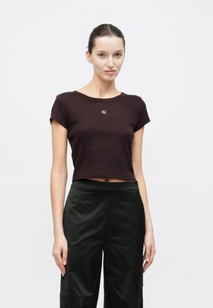 Bordowy krótki t-shirt z krótkimi rękawami, z okrągłym dekoltem i małą czarną naszywką z logo na środku. Matowa faktura.