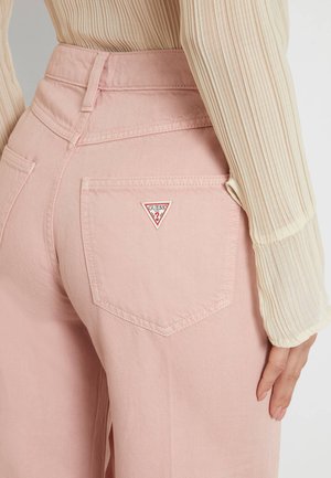 Šviesiai rožiniai džinsai su aukštu liemeniu, užpakaliniai kišeniai su trikampiu raudonai baltu "GUESS" logotipu ir glotnia tekstūra.