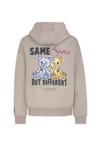 Beige hoodie met een gedrukte afbeelding van twee knuffelberen in blauw en geel, met de tekst "SAME Same BUT DIFFERENT" erboven.