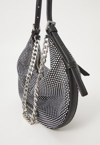 Black handbag covered in silver rhinestones with a chain strap and leather accents, featuring a curved shape and textured surface.