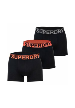 Trois paires de boxers noirs avec des ceintures élastiques marquées en noir et orange, deux avec « SUPERDRY » en orange et un en gris.