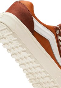 Ruskosneakerit valkoisilla yksityiskohdilla, joissa on teksturoitu kumipohja ja sileä päälliskangas. Yksityiskohtaiset tikkaus kantapäässä.