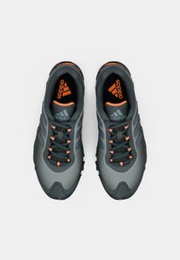 Hallid jooksujalatsid tekstureeritud sünteetilise pealsega, mustade paelte ja oranžide detailidega. Omavad kolme triipu ja pehmet tallapinda haarduvuse tagamiseks.