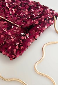 Burgundy paillet clutche med en glat tekstur. Har en gylden kædetræksrem og flad design. Bemærkelsesværdig for sine skinnende, overlappende pailletter.