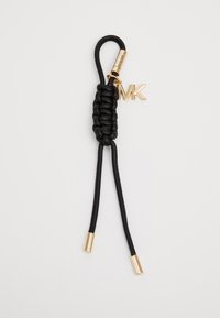 Porte-clés en cuir noir avec un centre tressé, des accents métalliques dorés et un charme logo "MK". Deux fines sangles en cuir noir s'étendent depuis la base.