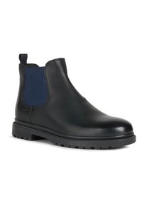 Zwarte leren Chelsea-boot met marineblauwe elastische zijpanelen, ronde neus, rubberen zool en trekloop; gladde textuur en minimale stikdetails.