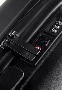 Valigia nera rigida con doppia chiusura e lucchetto approvato dalla TSA. Caratterizzata da un combinatore a rotella, maniglia robusta e superficie texturizzata per una migliore presa.