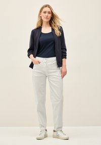 Chaqueta bomber navy, pantalones blancos de cintura alta y zapatillas blancas. Tela suave, corte relajado y bolsillos laterales en los pantalones.