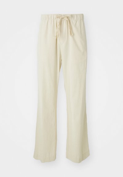 Pantalons beiges amples en tissu léger. Dotés d'une taille élastique avec cordon de serrage et d'un design à jambe évasée.