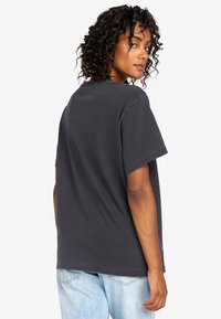 T-shirt in cotone grigio scuro con maniche corte e vestibilità morbida, con scollo a girocollo e dettagli di cucitura sottili.