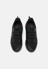Des baskets de sport noires avec une tige en mesh, des détails texturés et des lacets à motifs ; dotées d'une semelle en caoutchouc lisse et de languettes.